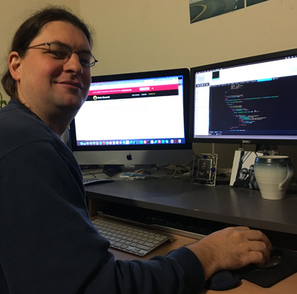 Matteo at his desk with code open on two monitors